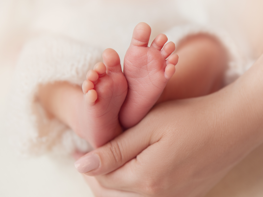 Newborn baby's feet on Mum's hand
