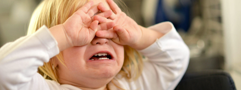 Child covering eyes crying