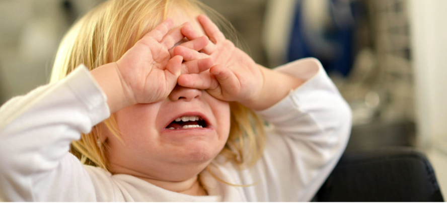 Child covering eyes crying