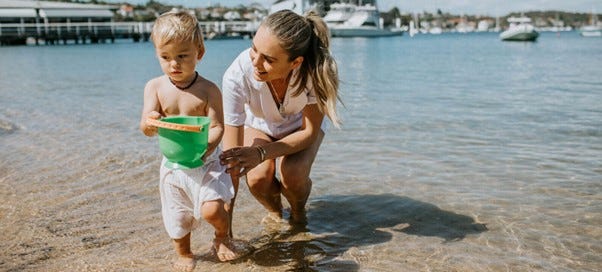 mum and son playing in the water at the beach