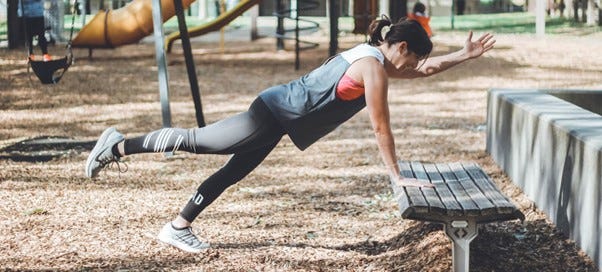 Woman doing core exercises on park bench
