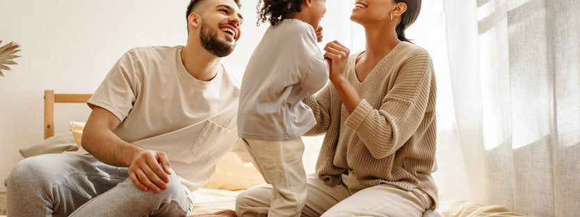 Parents playing with toddler on bed