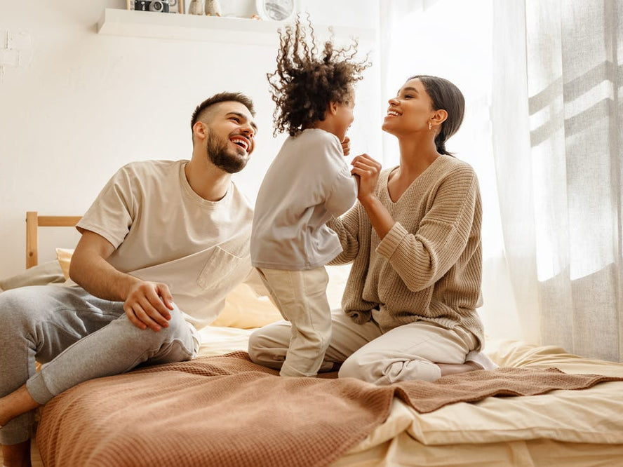 Parents playing with toddler on bed