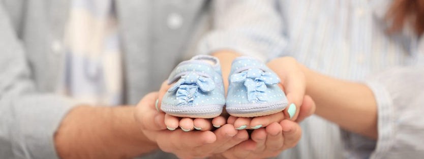 parents holding blue baby shoes