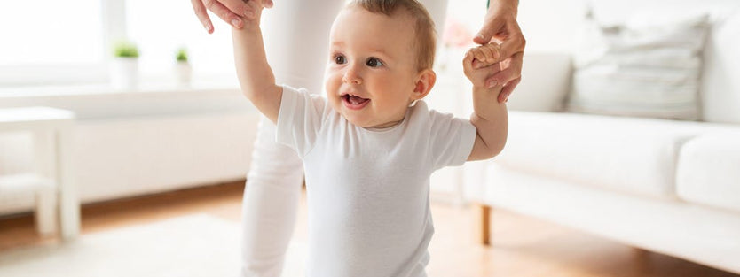 Infant learning to walk with the help of mum