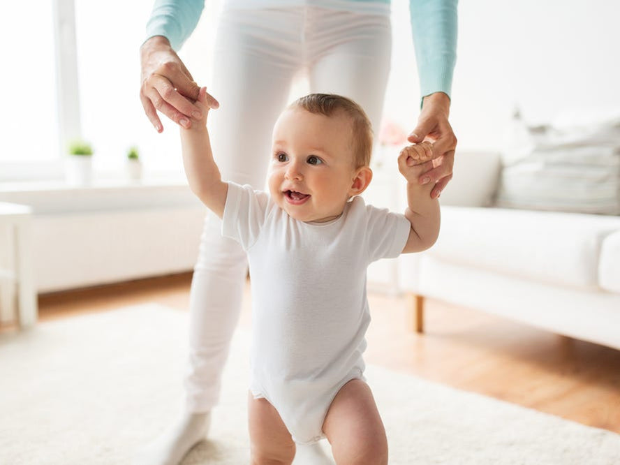 Infant learning to walk with the help of mum