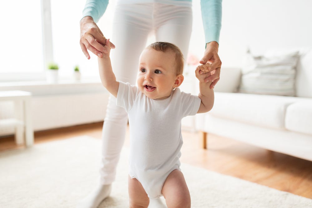 Infant learning to walk with the help of mum